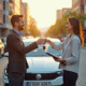 Personne souriante remettant les clés de la voiture lors d'une transaction en plein soleil